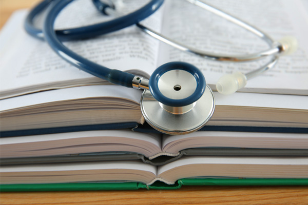 a stack of medical books with a stethoscope laid across the top