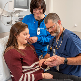 doctor checking patient’s hand with a nurse observing in the emergency room