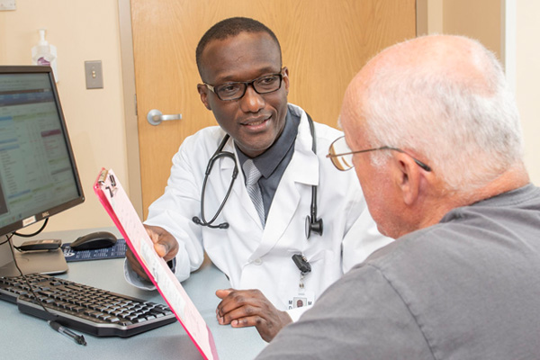 doctor mario lysse, holding a clipboard, consults with a patient