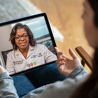 back view of a young woman having a video consultation with a female practitioner on a digital tablet