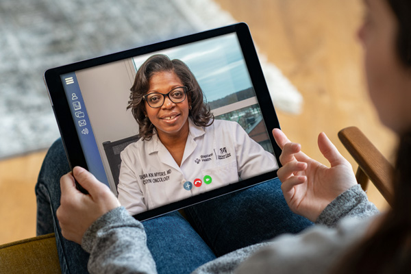 back view of a young woman having a video consultation with a female practitioner on a digital tablet