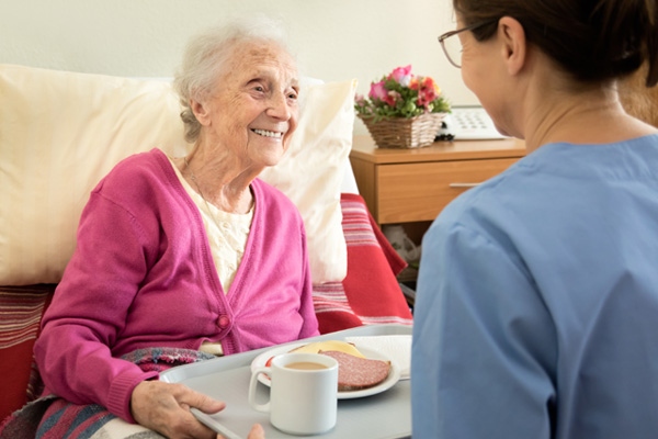 hospice patient sitting in bed with meal being cared for by provider