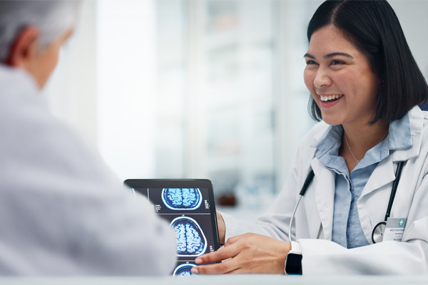 a neurologist showing a patient a computer with images of brain scans