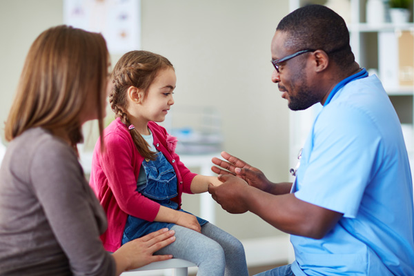 a doctor touching the hand of a pediatric patient while the mother is watching