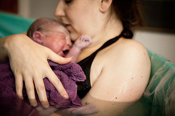 parent with infant in water birth tub