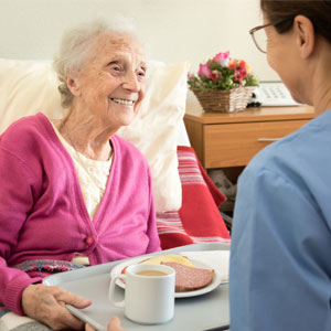 an old woman smiling as she is being handed a plate of food