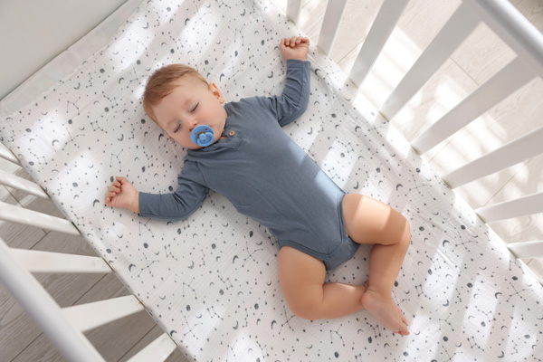 baby in a crib sleeping in a safe sleep position