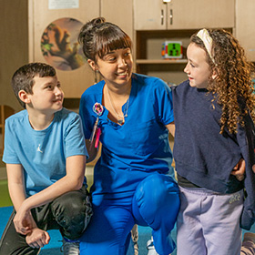 Two pediatric patients kneeling down with a Baystate employee