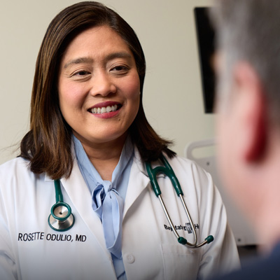 dr rosette odulio smiling in her white doctor's coat talking to a patient