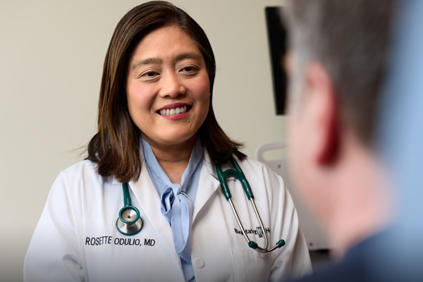 dr rosette odulio smiling in her white doctor's coat talking to a patient